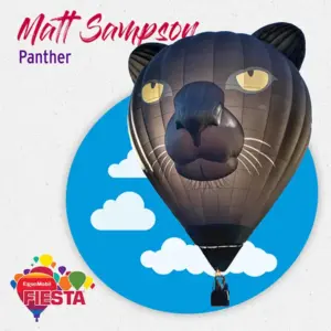 A hot air balloon shaped like a panther's head against a blue sky background with clouds.