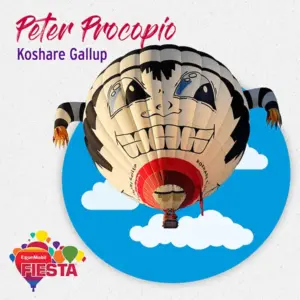 A whimsical hot air balloon with a cartoon face floats against a blue sky with clouds, advertising the ExxonMobil Fiesta event.