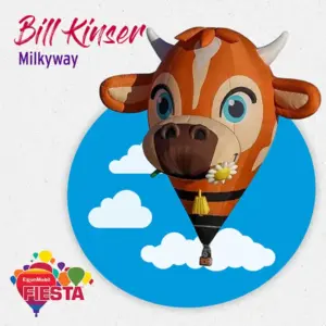 A cow-shaped hot air balloon from the Albuquerque International Balloon Fiesta floats against a blue sky with clouds, adorned with daisies.