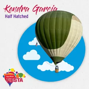 A green hot air balloon floats against a blue sky with clouds.