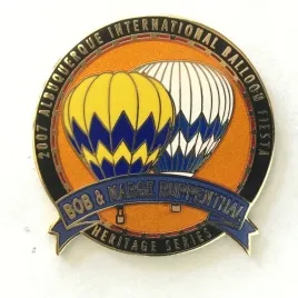 2007-Honoree-Bob-and-Marge-Ruppenthal Pin featuring two colorful hot air balloons with text "2007 Albuquerque International Balloon Fiesta" and "Bob & Kaege, Bisontennial Heritage Series" on a ribbon.
