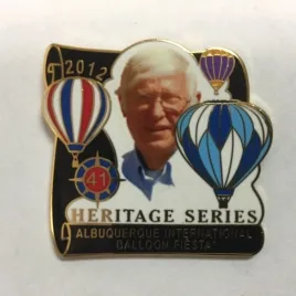2012-Honoree-Dick-Brown The image shows a commemorative pin featuring a person, hot air balloons, and text for the 2012 Albuquerque International Balloon Fiesta, Heritage Series.