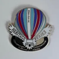 2023-Honoree-Chuck-Raskob A colorful hot air balloon pin features "Heritage Series" and "2023." It celebrates the Albuquerque International Balloon Fiesta with vibrant stripes and elegant details.